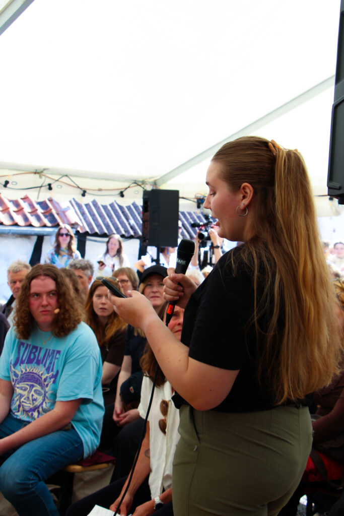 Billede af Rebecca der læser dilemmaer op til en talk på Folkemødet i 2025. 